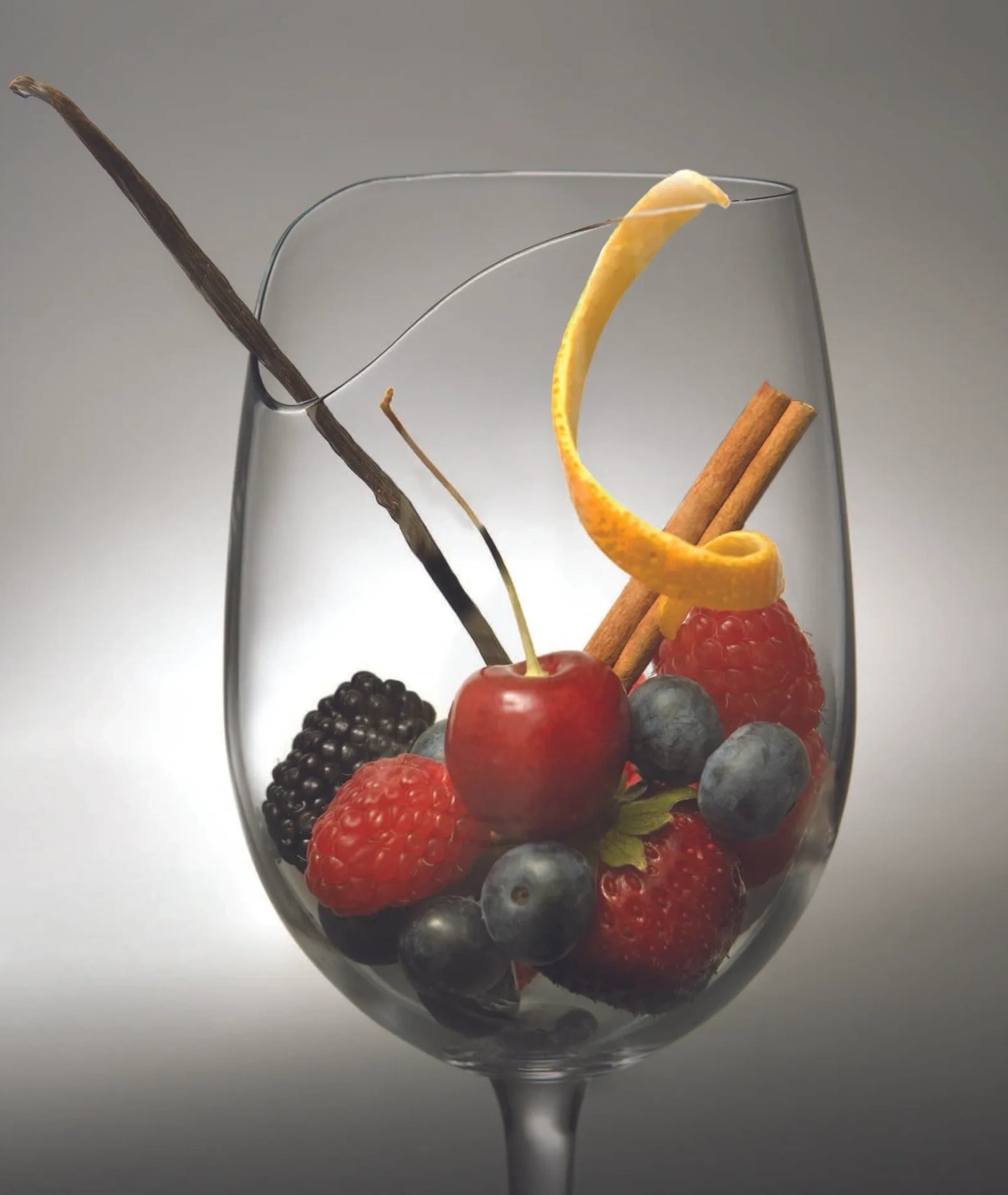 A Les Aromes glass holding berries, cherry, cinnamon and orange peel, with the Notch visible in the rim